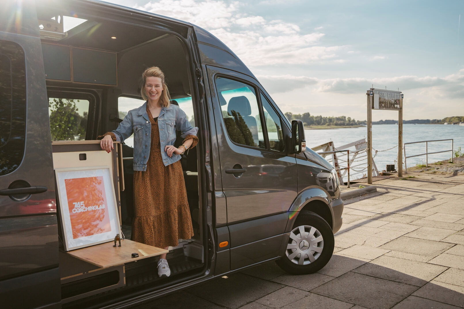 Britta Cornelißen in der offenen Tür ihres ausgebauten Vans stehend am Rheinufer