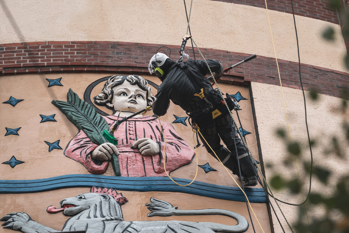 Industriekletterer seilt sich am Denkmal geschützten Wasserturm in Mönchengladbach ab und reinigt das Relief des Stadtwappens