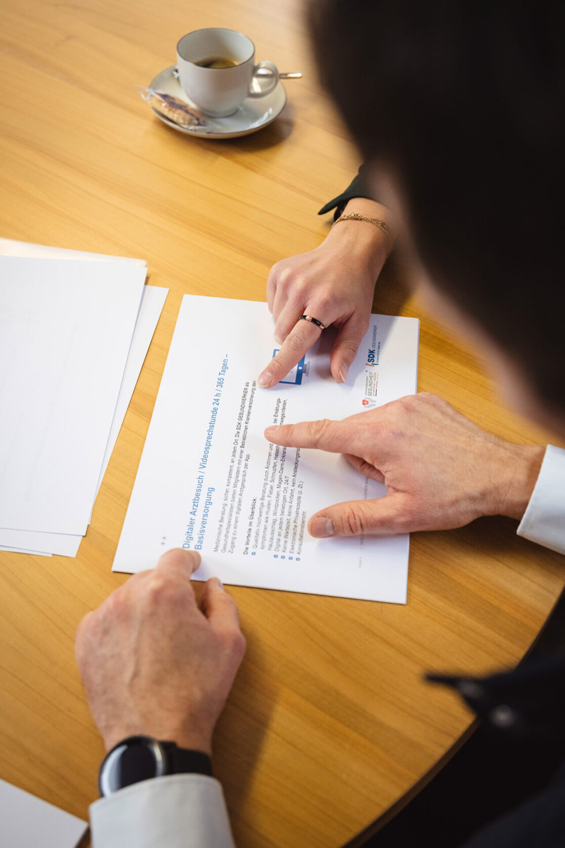 verschiedene Hände zeigen auf Blätter auf dem Tisch