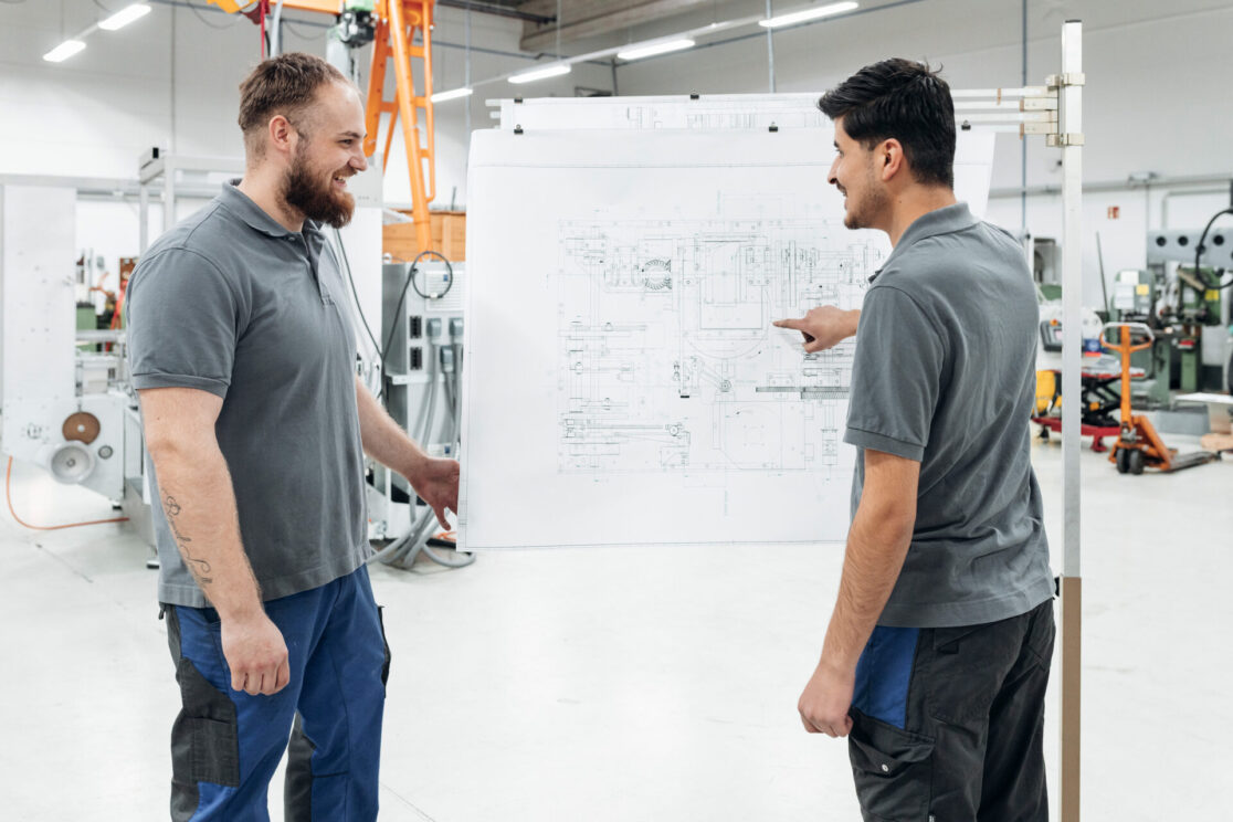 Businessreportage Rasch Verpackungsmaschinen Köln- Zwei Auszubildende der Firma Rasch Verpackunsgmaschinen stehen an einer Zeichnung